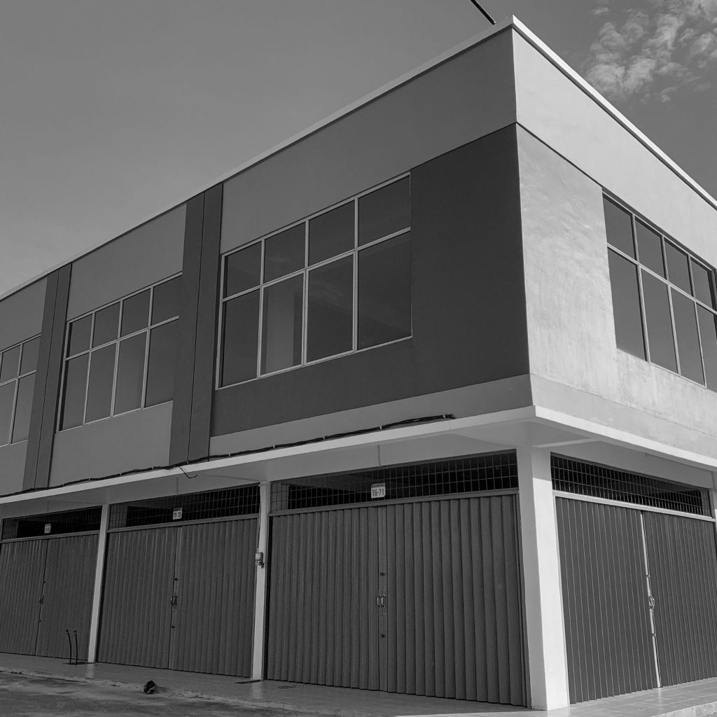 Angle shot of a modern commercial building with large rectangular glass windows and a white corner facade, viewed from ground level.