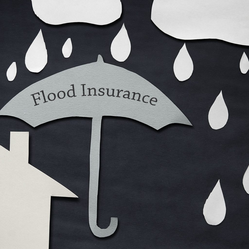 Abstract paper-cut illustration with white raindrops on a dark background and a curved gray label reading Flood Insurance, suggesting flood coverage.